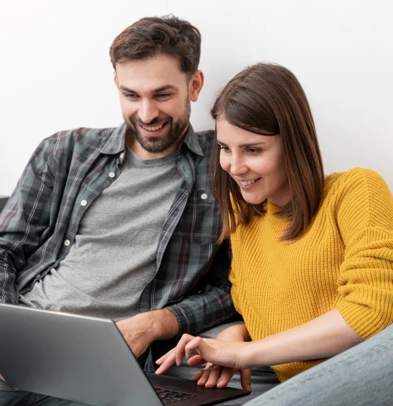 Un couple remplit une demande sur un ordinateur portable, dans son salon