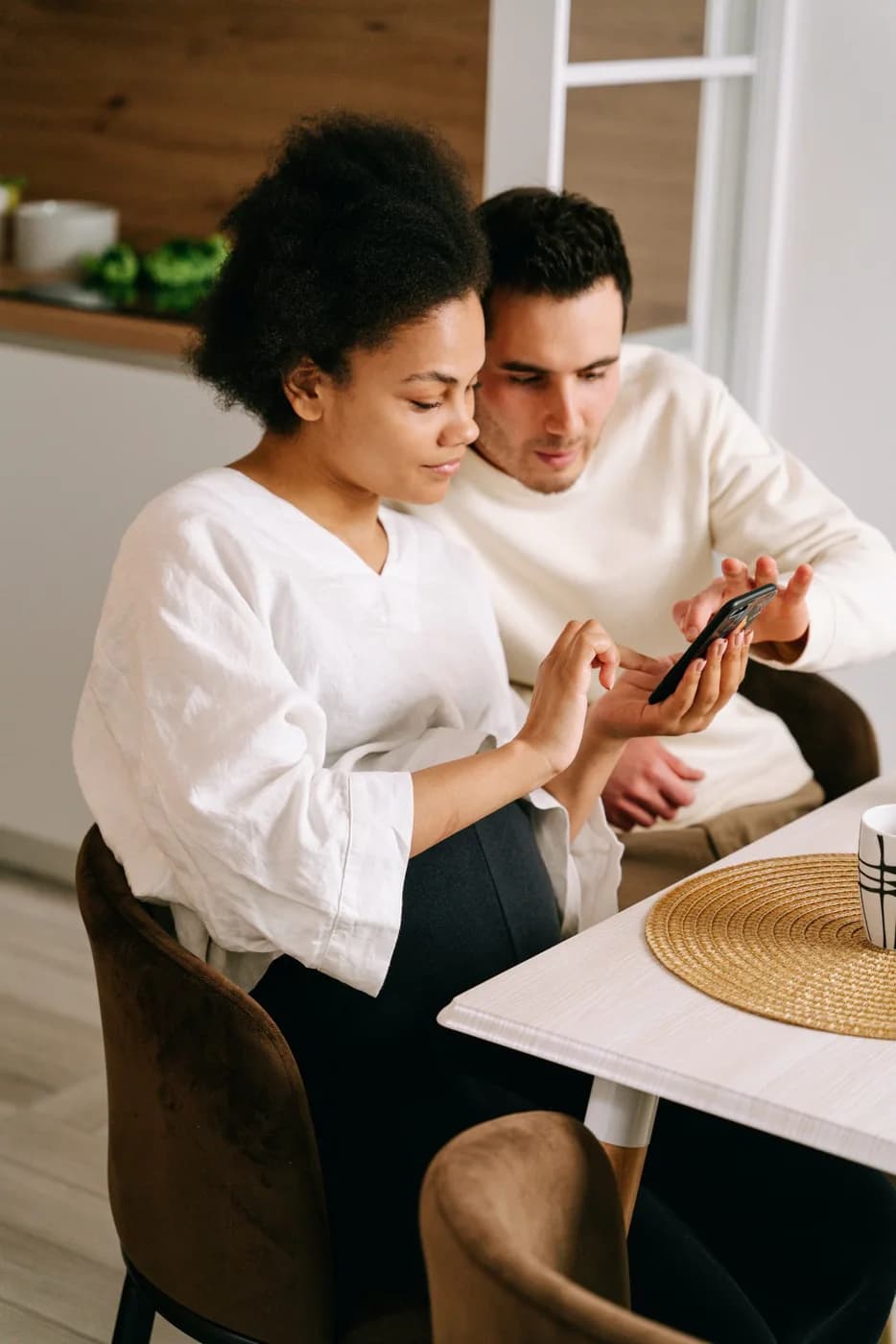Un couple attablé consulte son téléphone ensemble