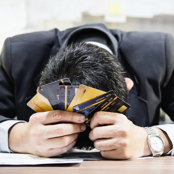 Un homme en costume tenant une pile de cartes de crédit, symbolisant un prêt personnel avec un mauvais crédit.