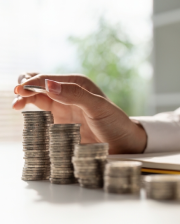 une main empilant des pièces de monnaie