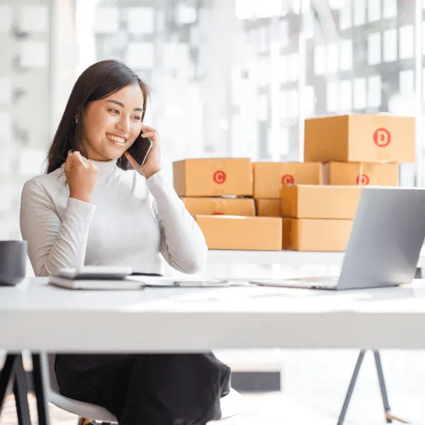 Une femme assise à un bureau avec un ordinateur portable et des boîtes