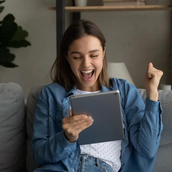 Une femme assise sur un canapé, tenant un iPad, illustrant le concept de prêt personnel.